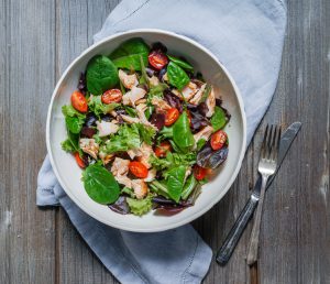 Mixed Green Salad with Grilled Salmon, Quinoa and Avocado on Wood Background/ Healthy Food Concept